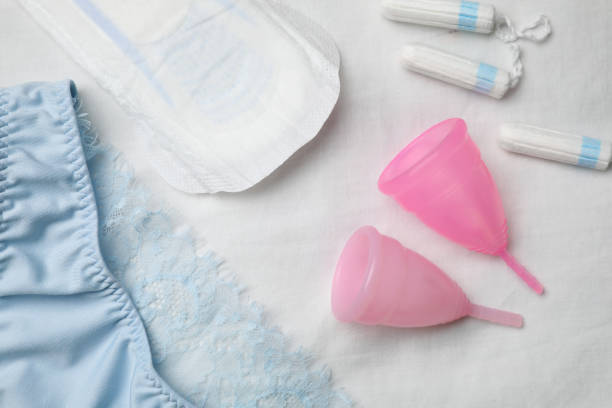 Woman's panties, menstrual pad, cups and tampons on white fabric, flat lay Woman's panties, menstrual pad, cups and tampons on white fabric, flat lay menses stock pictures, royalty-free photos & images