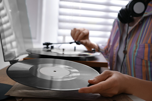 Young woman using turntable at home, closeup