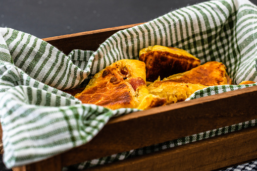 Freshly baked homemade ham and cheese puff pastry in a rustic crate.