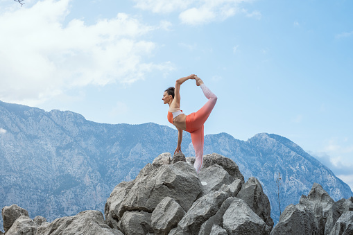 Woman doing yoga on mountain cliff.