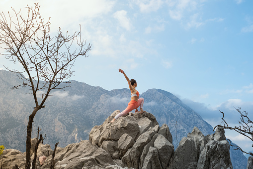 Woman doing yoga on mountain cliff.