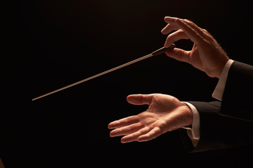 Concert conductor hands with baton on back background