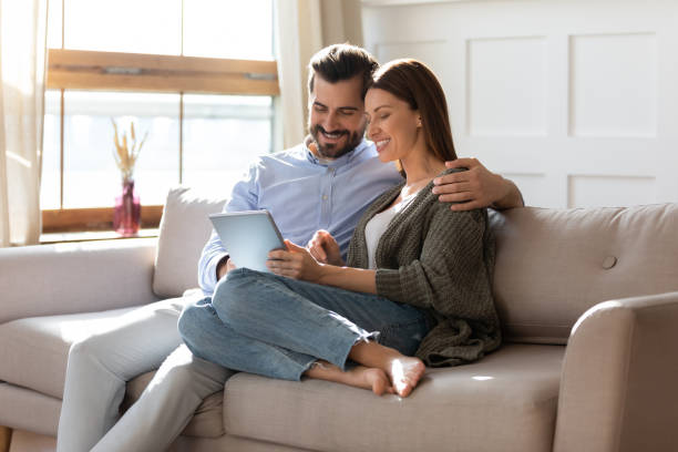istock Happy couple relax on sofa using tablet together 1319593811