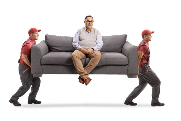 istock Movers carrying a corpulent mature man seated on a sofa 1319596827