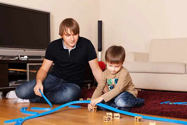 Father is playing with son in toy railroad