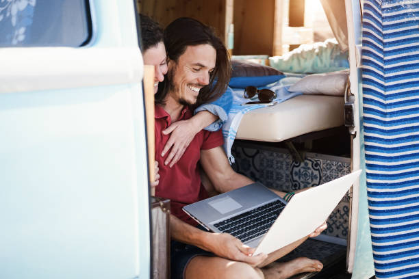 istock Happy couple using laptop computer inside minivan during road trip vacation - Focus on man face 1319598005