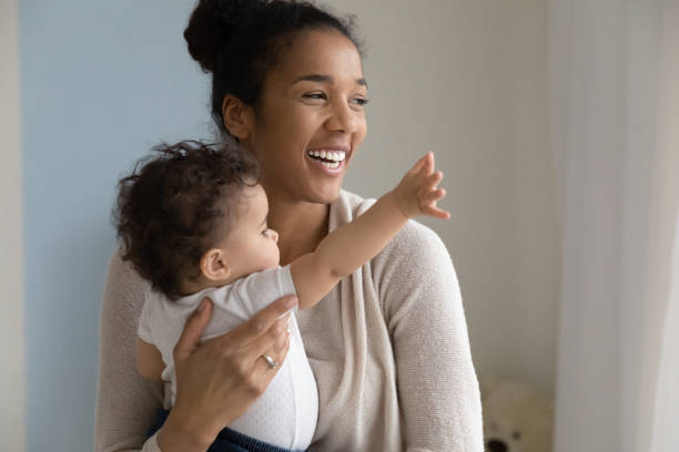 大喜び若い民族ママは小さな赤ちゃんの娘を抱きしめる - newborn baby african ethnicity little girls ストックフォトと画像