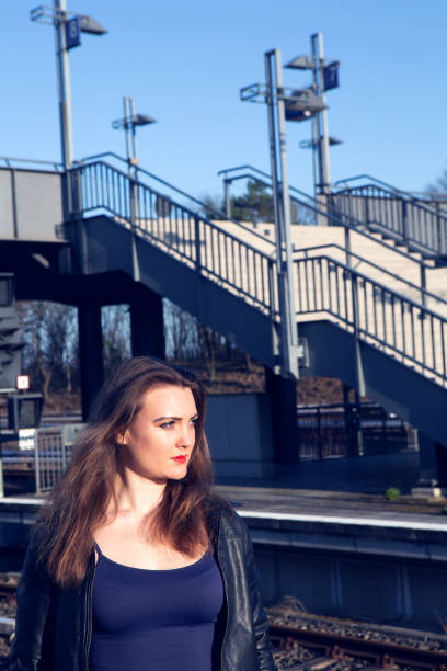 молодая женщина в кожаной куртке ждет на платформе на вокзале - platform rocker стоковые фото и изображения
