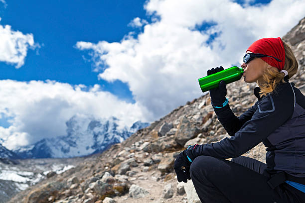 Woman drinking water in mountains stock photo
