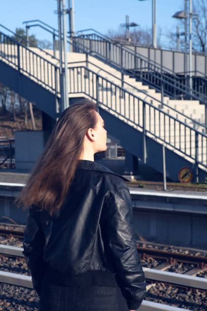молодая женщина в кожаной куртке ждет на платформе на вокзале - platform rocker стоковые фото и изображения