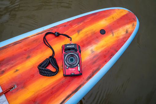 Fort Collins, CO, USA - May 9, 2021: Compact, waterproof Olympus Stylus Tough TG-5 camera on a rear deck of a stand up paddleboard by Mistral.