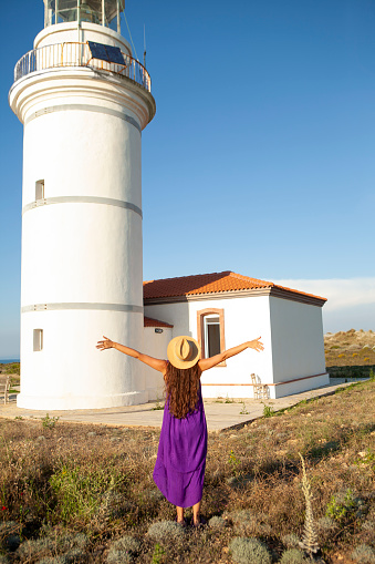 Cheerful young woman arms outstretched  to the lighthouse