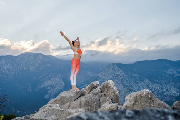 Beautiful woman makes exercises of yoga, the top of the mountain.