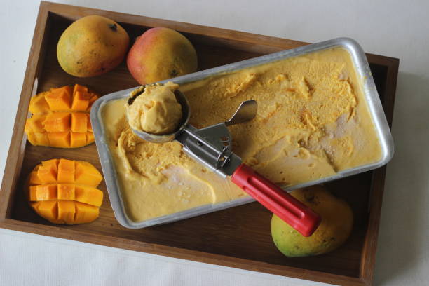 scooping von mango-eis zum servieren aus einem tablett draußen aus gefrieren - refrigerator healthy eating mango fruit stock-fotos und bilder