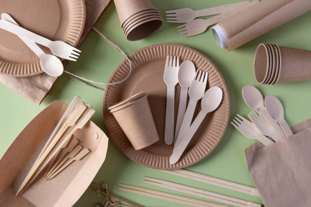 istock Disposable biodegradable tableware on craft paper plates - forks, spoons, glasses, wooden and bamboo skewers, sushi sticks, parchment. Zero Waste. View from above 1319613277