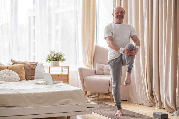 istock Elderly man practicing yoga or fitness standing on tree pose at home. 1319614834