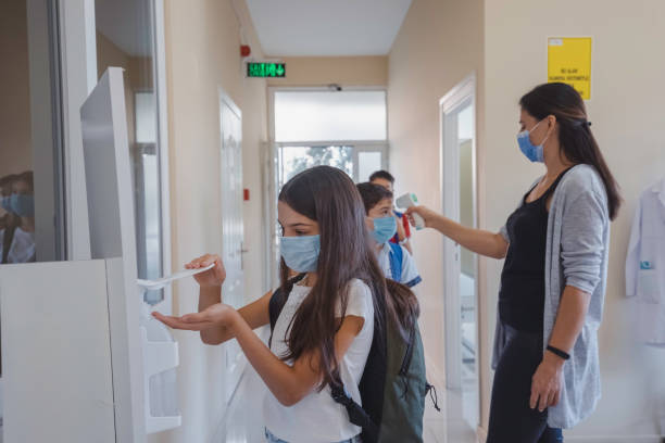 istock Little girl disinfecting hands while entering school. 1319622527