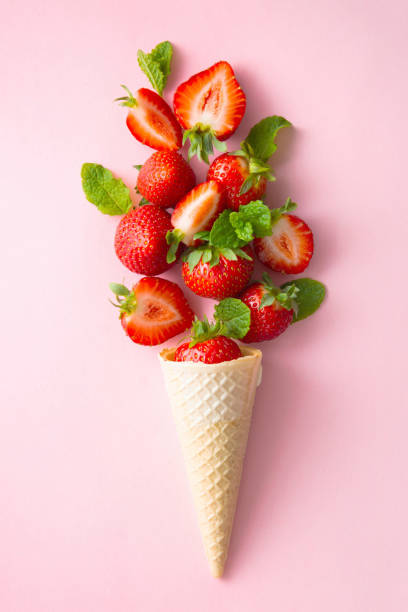 istock Ice cream waffle cone with fresh srawberries on pink background, top view. 1319622695