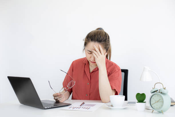 una mujer de negocios estuvo cansada del trabajo durante mucho tiempo, se estaba tomando un descanso para relajarse del trabajo, se sentó en su oficina y pasó mucho tiempo usando el ordenador portátil causando fatiga. concepto de síndrome de oficina. - posture office isolated physical injury fotografías e imágenes de stock