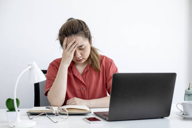 una mujer de negocios estuvo cansada del trabajo durante mucho tiempo, se estaba tomando un descanso para relajarse del trabajo, se sentó en su oficina y pasó mucho tiempo usando el ordenador portátil causando fatiga. concepto de síndrome de oficina. - posture office isolated physical injury fotografías e imágenes de stock