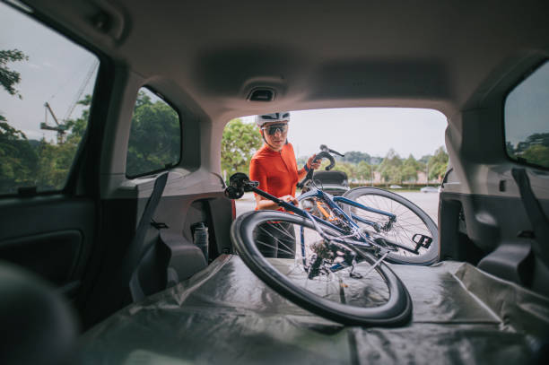 Asian chinese woman professional cyclist taking down her bicycle from the car trunk ready to cycle Asian chinese woman professional cyclist taking down her bicycle from the car trunk ready to cycle cycling vest photos stock pictures, royalty-free photos & images