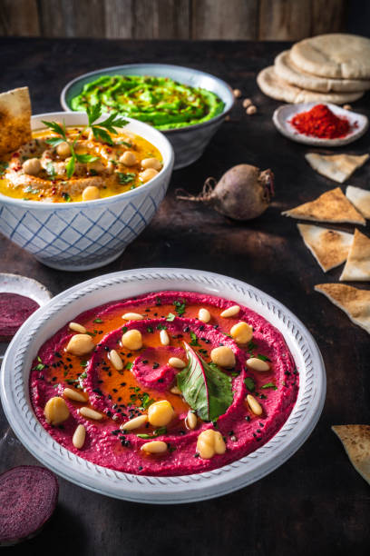 istock Beetroot pink hummus bowl closeup with pita flatbread dipping on dark wood table 1319627393