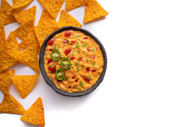 istock cheedar cheese dip sauce with Nacho chips with tomato and chili isolated on white 1319627697