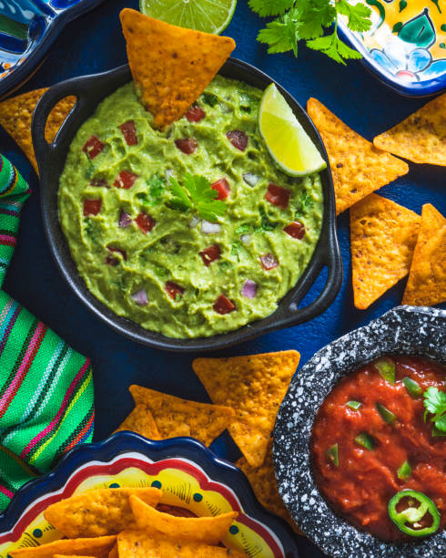 istock Guacamole avocado sauce and Mexican tomato salsa dip with nacho chips on blue 1319627713