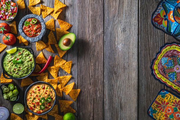 istock Mexican dip sauces guacamole, cheedar dip, tomato salsa and pico de gallo with Nacho chips mexican food on wood 1319627736