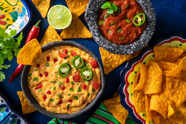 istock Cheedar cheese dip and Mexican tomato salsa dip with nacho chips on dark blue 1319627750