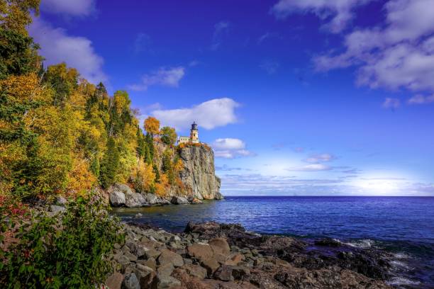 Split Rock Lighthouse on Lake Superior rocky shoreline on sunny day stock photo