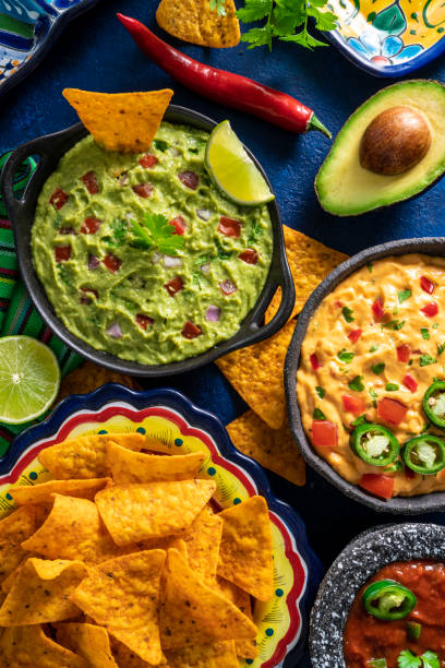 istock Mexican dip sauces guacamole, cheedar dip, tomato salsa and pico de gallo with Nacho chips 1319628403