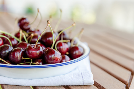 Plate full of cherries on wooden table.