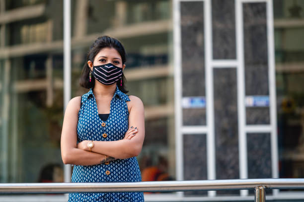 Outdoor image of Young Asian/ Indian woman wearing face mask for protection with pollution or viruses, Corona virus or COVID-19. Concept of prevention from harmful viruses with Single person, casual clothing, horizontal composition with extra copy space.
