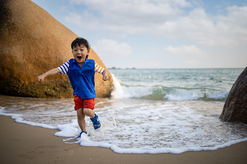 Close portrait of a boy run holding a colorful kite group on the string on the beach smiling over the sky during vacation