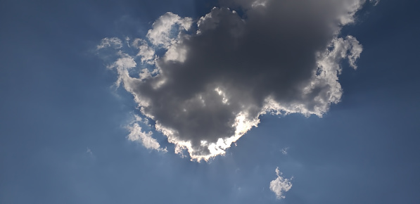 the sun is hiding behind a cloud in the blue sky