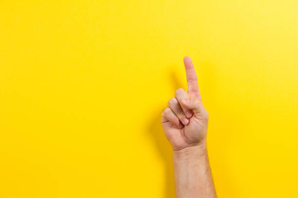 de hand die van de mens één vinger op gele achtergrond toont - wijsvinger stockfoto's en -beelden