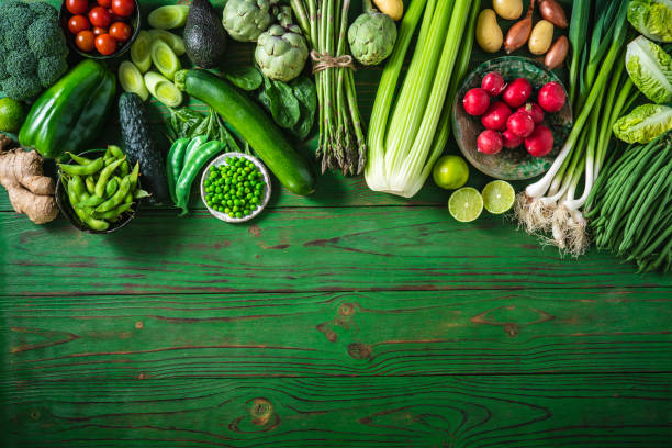 Vegan vegetables on green wooden table copy space
