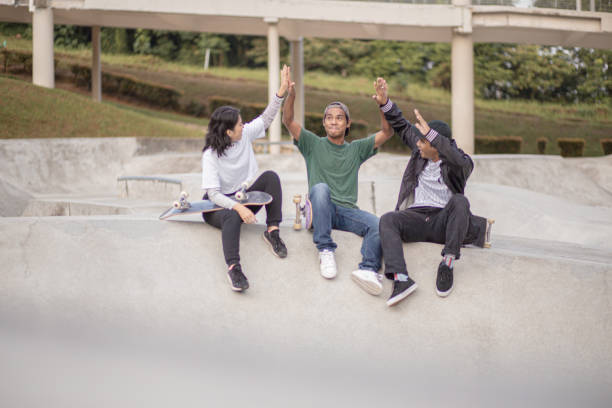 istock Asian skateboarders sitting taking a break and talking at skateboard park 1319638123
