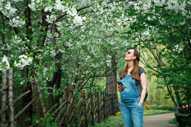 istock Pregnant woman making photos using smartphone in blooming park 1319638158