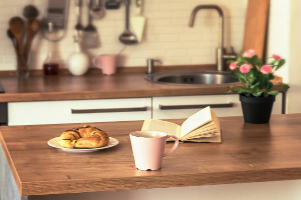 istock Coffee latte, book and croissant on wooden table. Modern kitchen interior background. Shallow depth of field 1319639267
