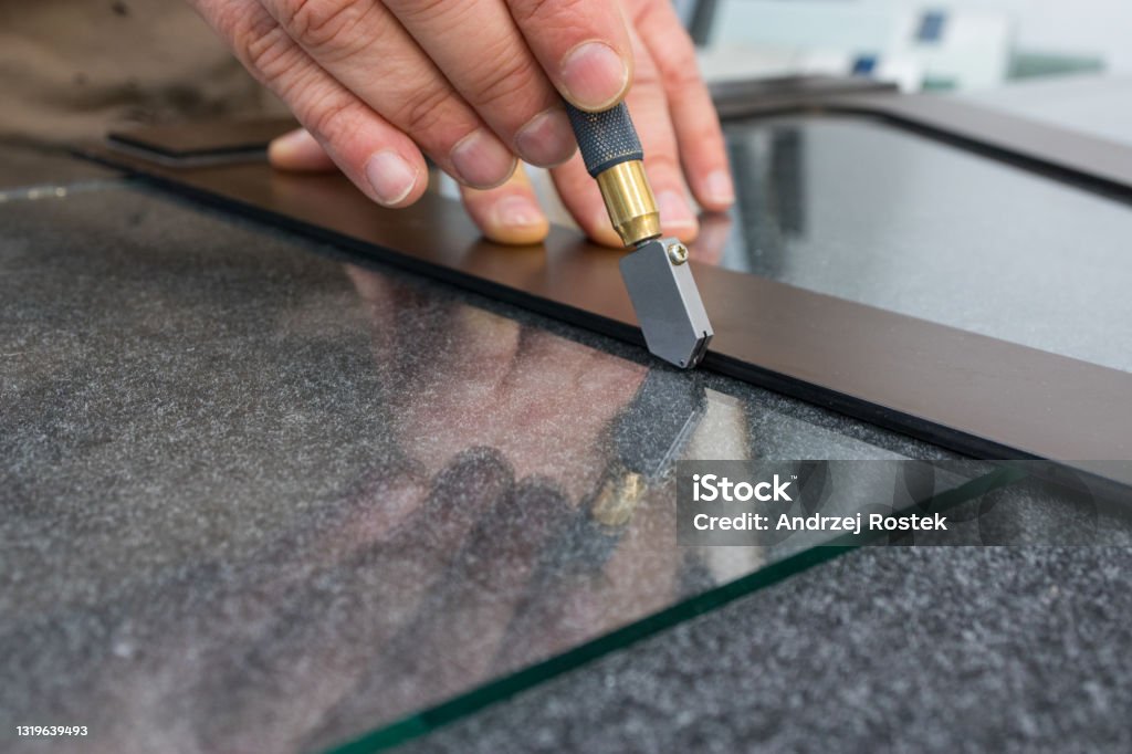 The glazier cuts the glass with a hand-held cutting tool. Handicraft plant, Close up Glass - Material Stock Photo