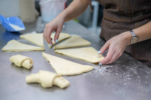 istock Young woman making croissants in bakery 1319641235