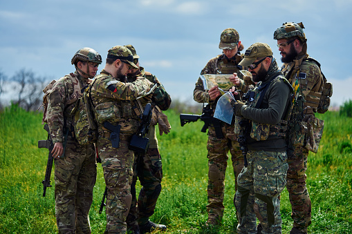A group of airsoft players in military uniform are examining a map.