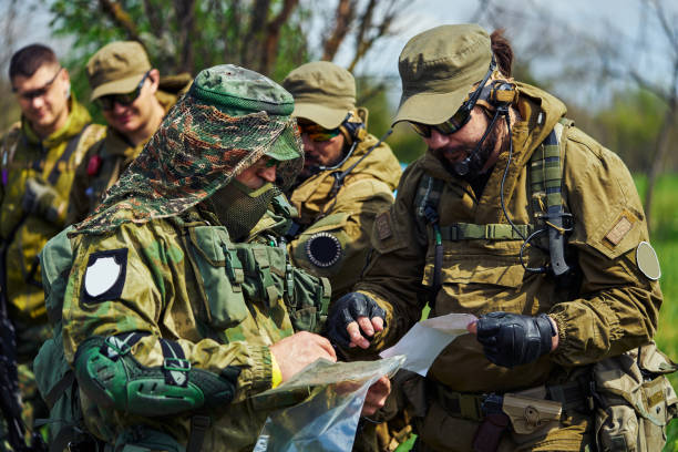 eine gruppe von airsoft-spielern in der uniform russischer soldaten beobachtet eine karte - airsoft gun stock-fotos und bilder