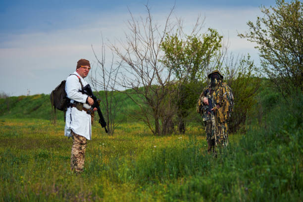 airsoft graczy w mundurze medyka i snajpera z bronią w rękach - hunting two people camouflage rifle zdjęcia i obrazy z banku zdjęć