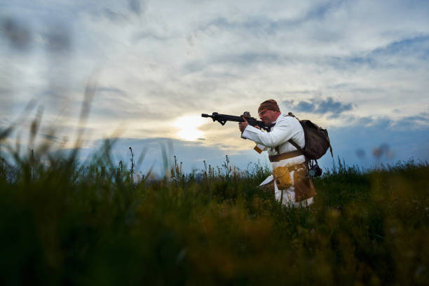 airsoft jogador em um terno médico com uma metralhadora nas mãos à noite no campo - conciliator - fotografias e filmes do acervo