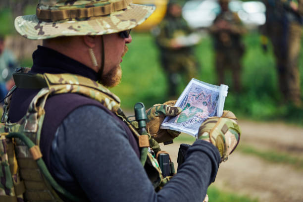 airsoft player em uniforme militar examinando um mapa - conciliator - fotografias e filmes do acervo