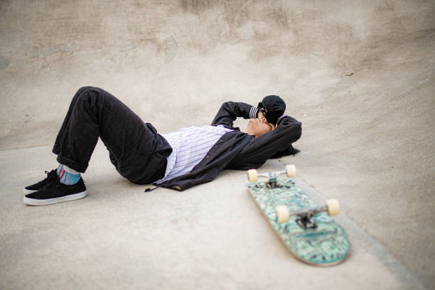 istock Asian skateboarder taking rest in the public skateboarding park during weekend 1319643458