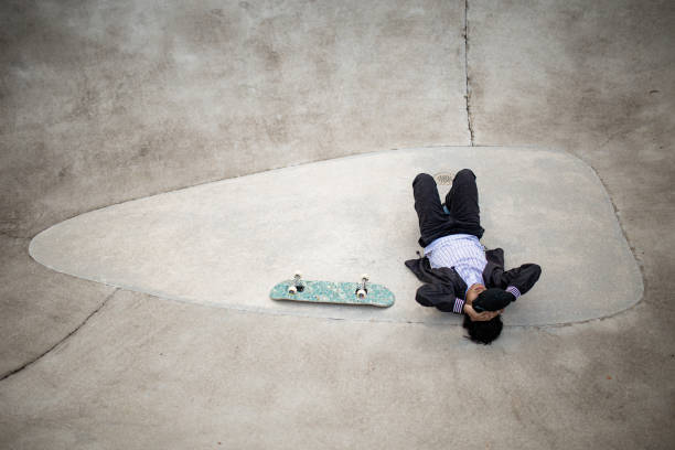 istock Asian skateboarder taking rest in the public skateboarding park during weekend 1319643459